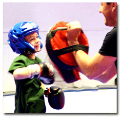 Child hitting martial arts pads in a childrens kickboxing class